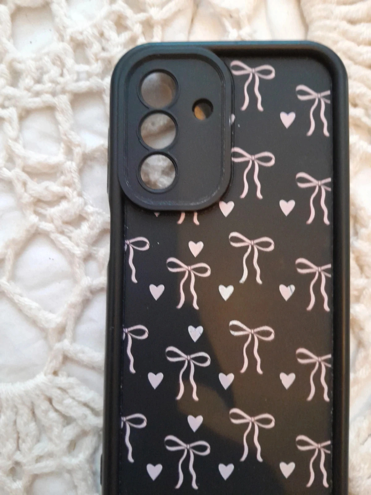 Zwarte telefoonhoes versierd met een herhalend patroon van kleine strikken en witte hartjes. – photo 2